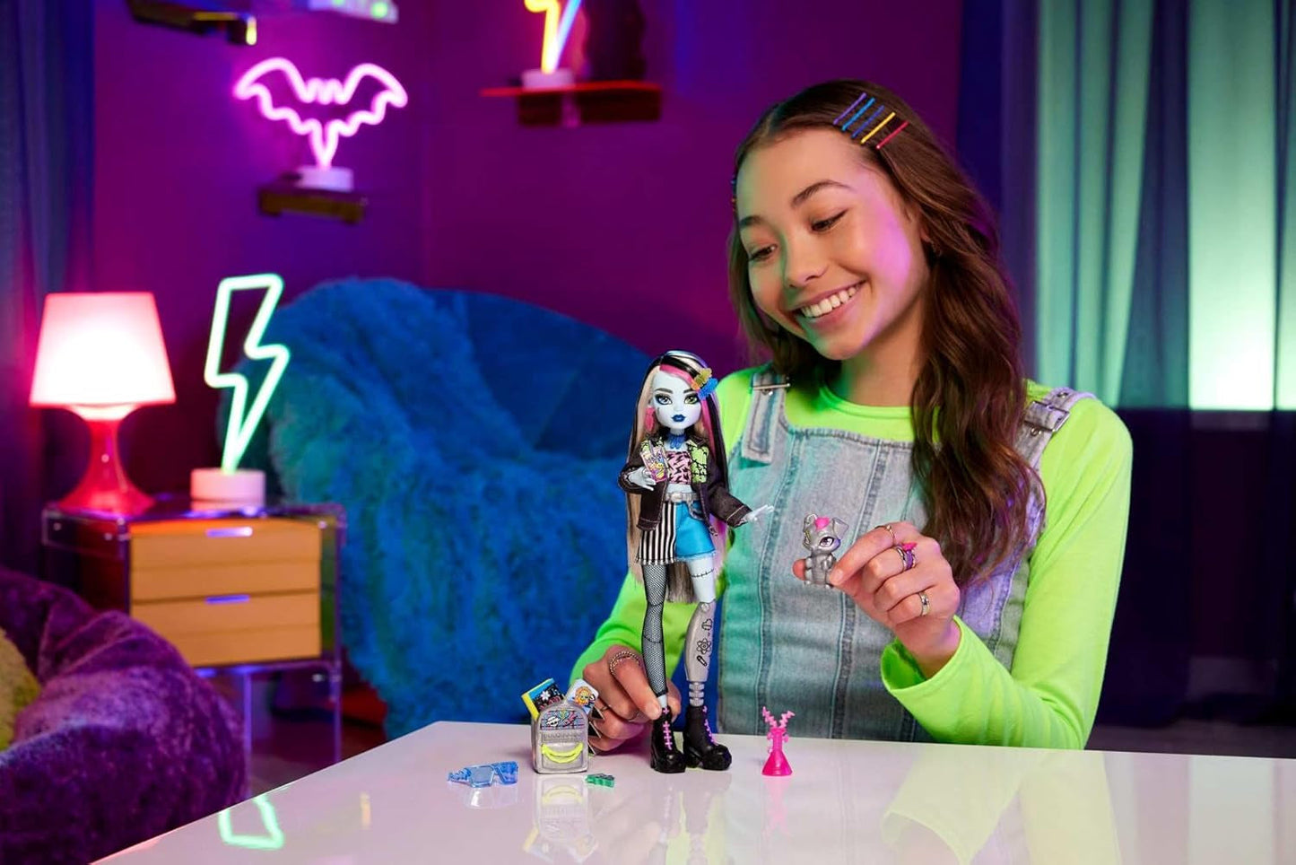 Muñeca Monster High Frankie Stein con chaqueta vaquera y pantalones cortos, también incluye su cachorro Watzie y accesorios como mochila, merienda y libreta, HXH73